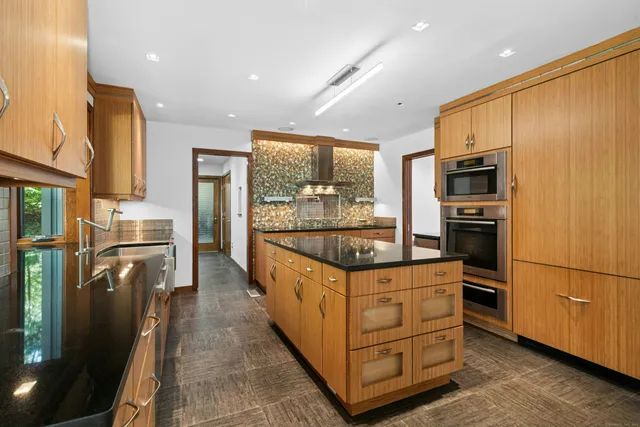 a kitchen with stainless steel appliances granite countertop a refrigerator a stove and a sink
