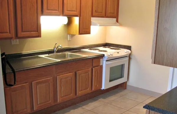 a kitchen with granite countertop a sink a stove and cabinets
