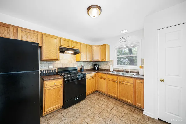 a kitchen with granite countertop a refrigerator stove top oven and sink