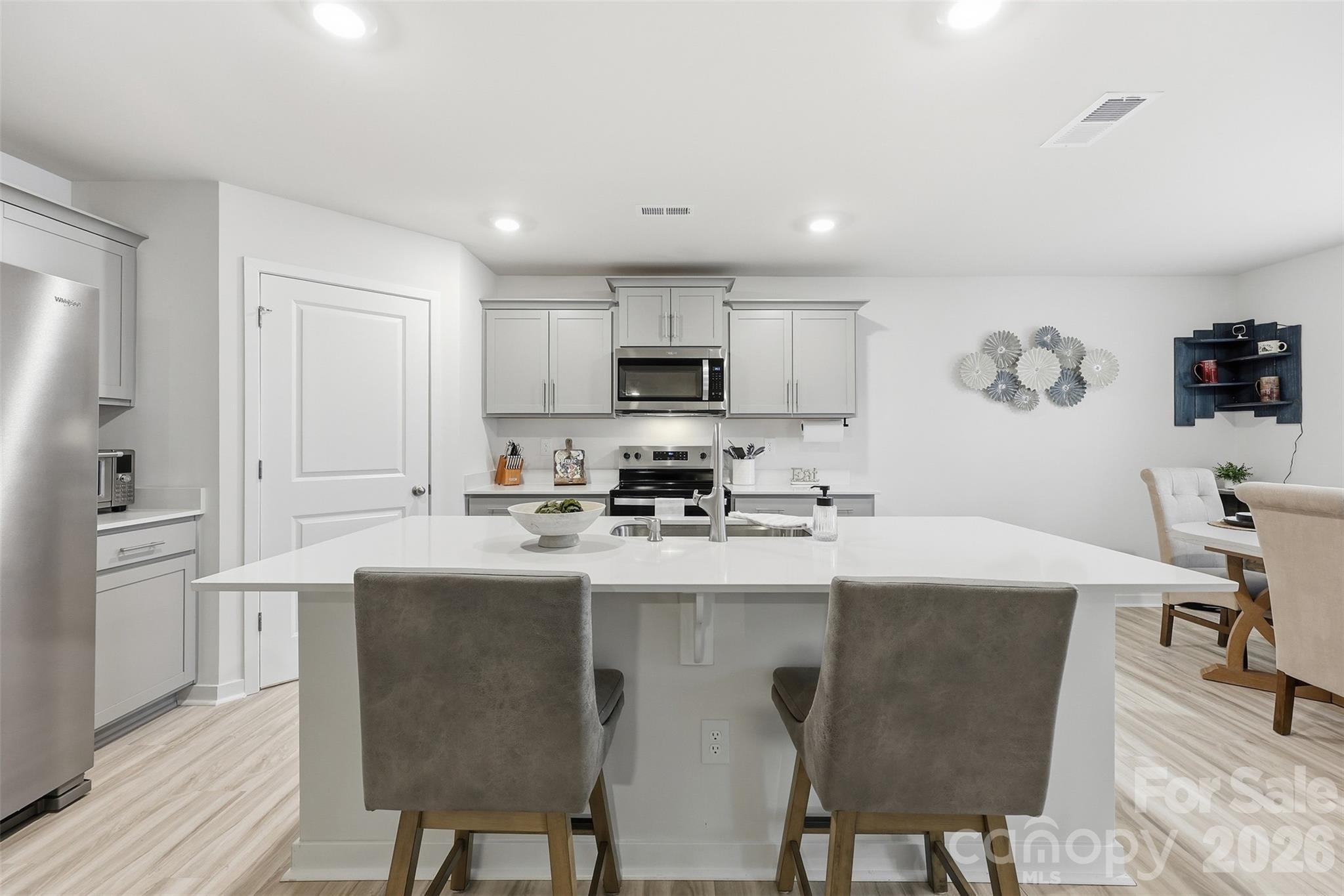 586 North Sparkleberry Street Chester, SC 29706 - Photo 8 of 36 a kitchen with stainless steel appliances granite countertop a stove a sink a microwave a refrigerator a dining table and chairs with wooden floor