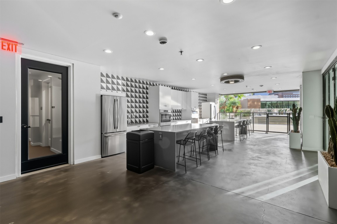 800 Embassy Drive, Unit 320 Austin, TX 78702 - Photo 16 of 23 a kitchen with stainless steel appliances granite countertop a refrigerator a sink a stove and a dining table with wooden floor