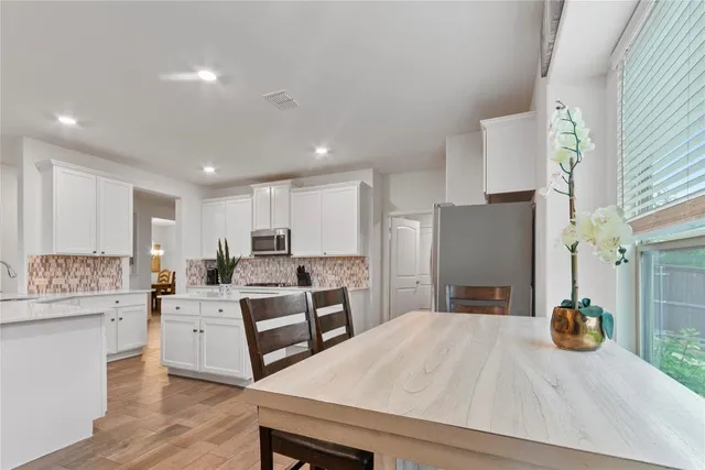 a kitchen with stainless steel appliances kitchen island granite countertop a refrigerator a stove and a sink with wooden floor