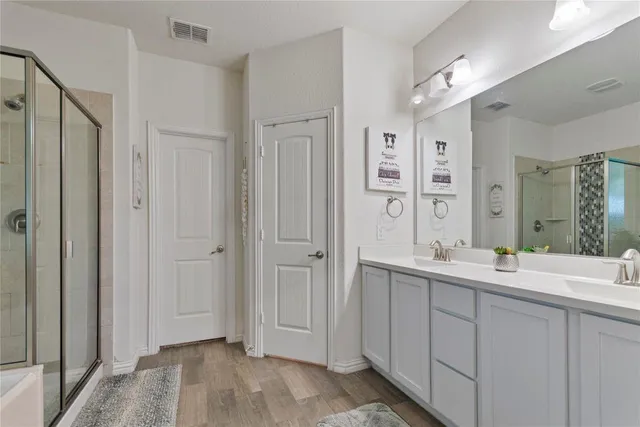 a spacious bathroom with a double vanity sink a large mirror and shower