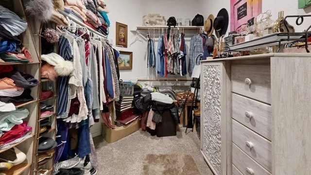 a view of walk in closet with clothes and shoes