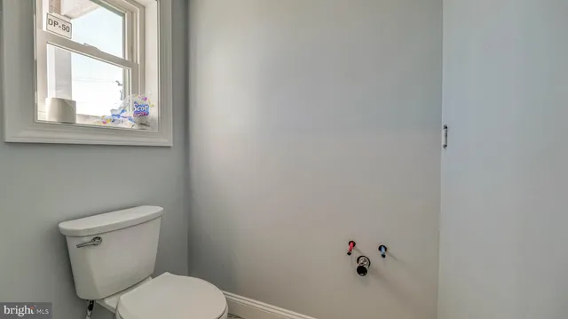 a white toilet sitting in a bathroom next to a window