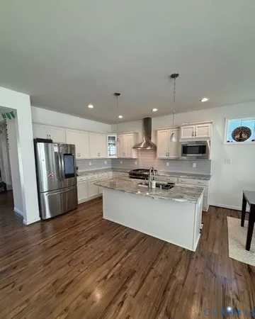 a kitchen with refrigerator and wooden floor