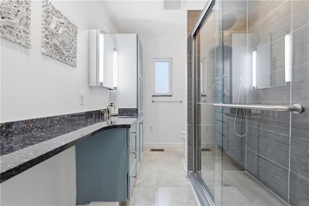 187 42nd Street Pittsburgh, PA 15201 - Photo 15 of 26 a bathroom with a granite countertop sink a mirror and a shower