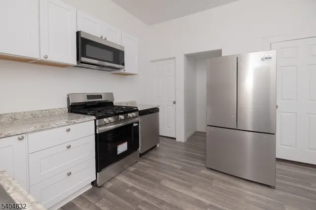a kitchen with stainless steel appliances white cabinets and wooden floor