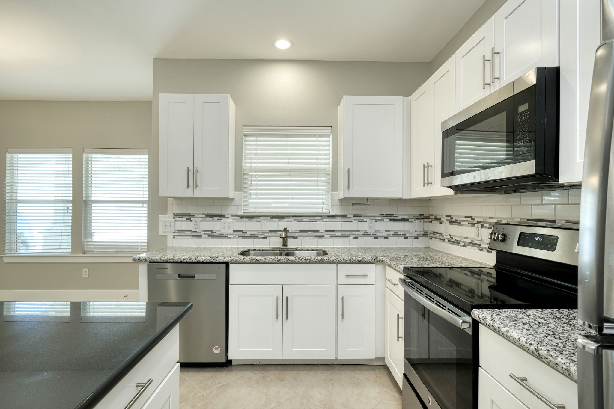 615 Spring Street, Unit 3 Round Rock, TX 78664 - Photo 3 of 14 A well-appointed kitchen features white cabinetry, granite countertops, and modern stainless steel appliances.