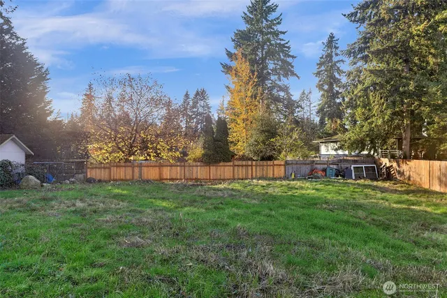 a view of a yard with large trees and a barn
