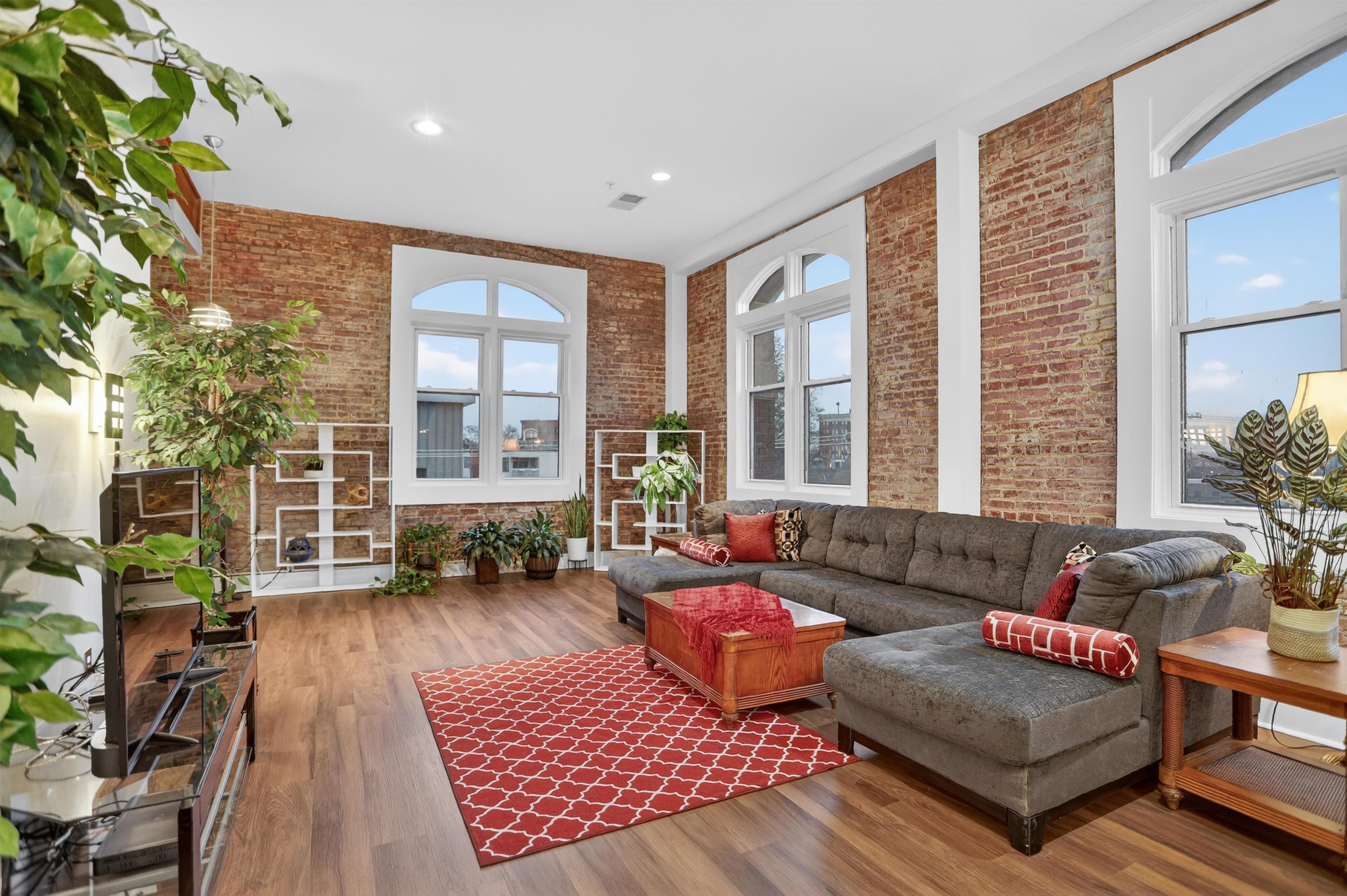 435 South Front Street, Unit 307 Memphis, TN 38103 - Photo 1 of 40 Living room featuring wood finished floors, recessed lighting, brick wall, wood beams and wall of windows.