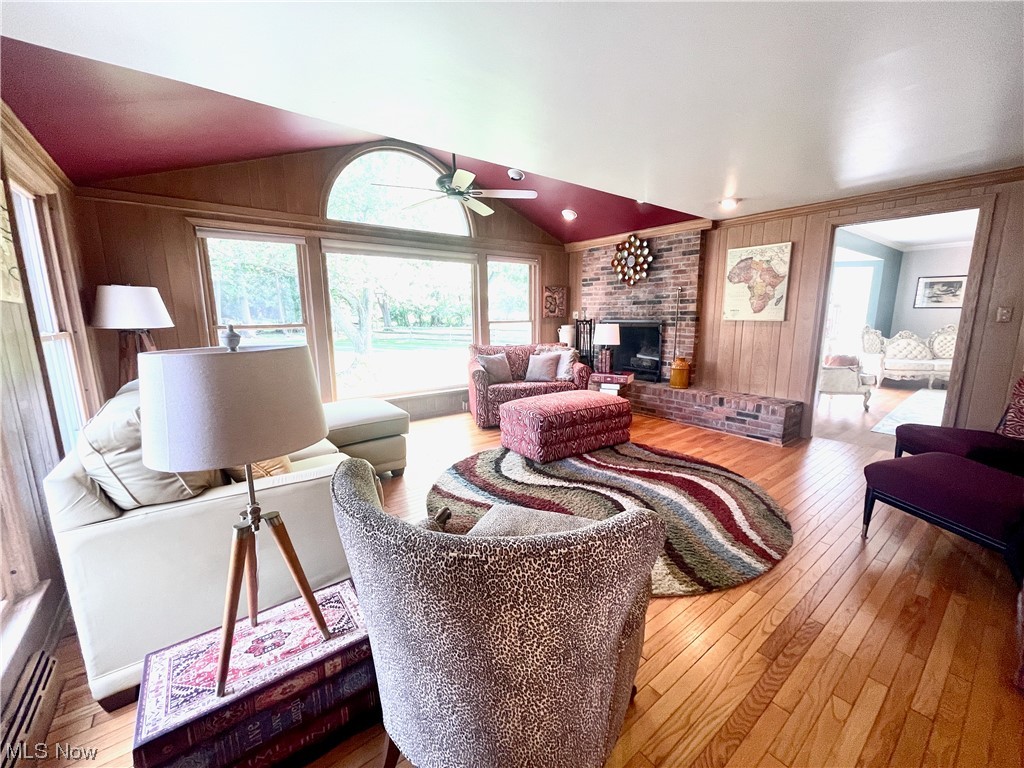 1507 Clubside Road Lyndhurst, OH 44124 - Photo 11 of 32 Hardwood floored living room featuring brick wall, a fireplace, lofted ceiling, wood walls, and ceiling fan