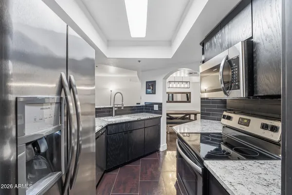 a kitchen with granite countertop stainless steel appliances sink stove microwave and cabinets