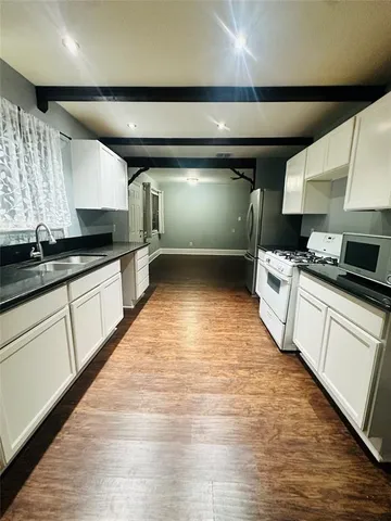 a kitchen with stainless steel appliances granite countertop a sink a stove and a wooden floors