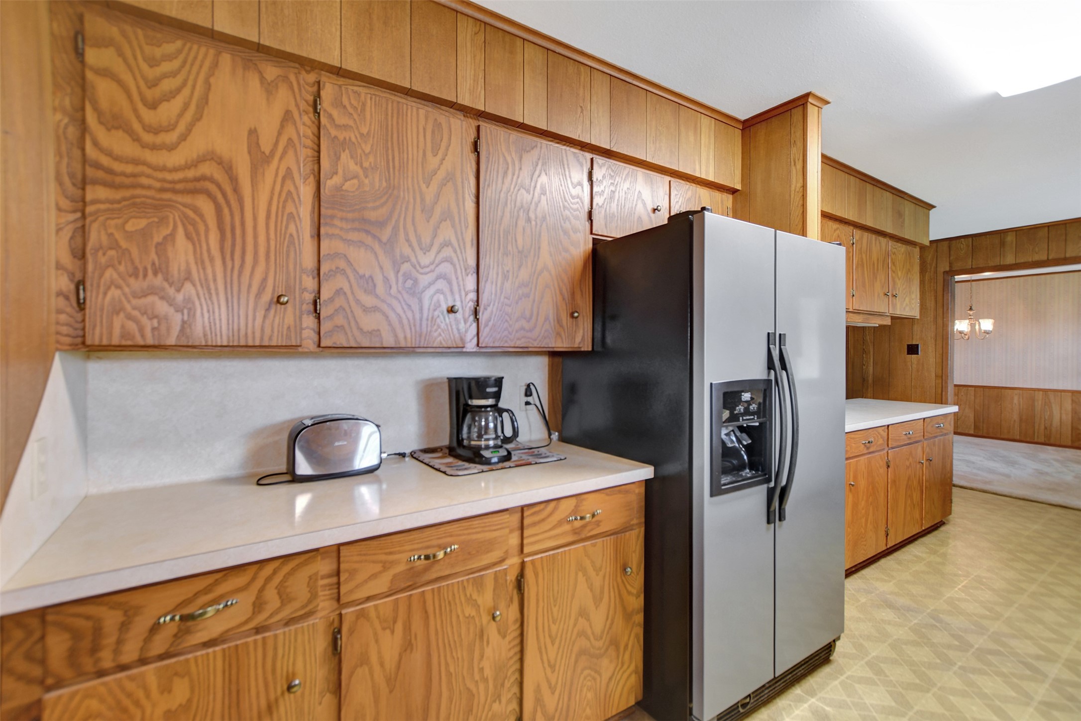 341 South S Loop Bellville, TX 77418 - Photo 14 of 33 This kitchen features vintage wood cabinetry, a modern stainless steel refrigerator, and ample counter space. The room has a cozy, retro feel with a view into an adjoining dining area.