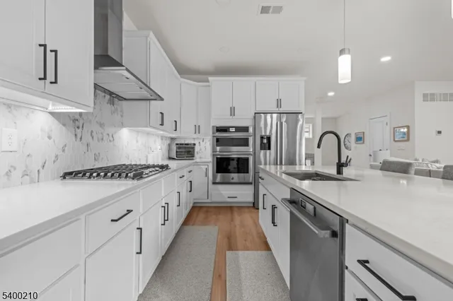 a kitchen with kitchen island white cabinets and stainless steel appliances