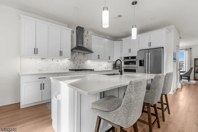 a kitchen with stainless steel appliances granite countertop a table chairs refrigerator and microwave