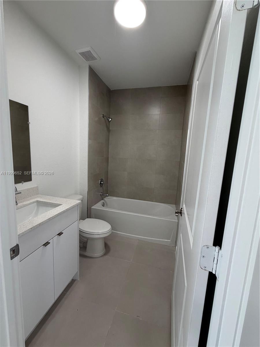 8034 Northwest 14th Place, Unit 8034 Miami, FL 33147 - Photo 5 of 14 a bathroom with a granite countertop sink toilet and shower