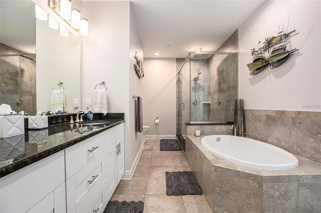 a bathroom with a granite countertop double vanity sink a mirror and a bathtub