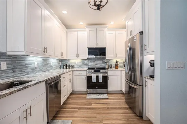 a kitchen with stainless steel appliances granite countertop a stove a refrigerator and a sink
