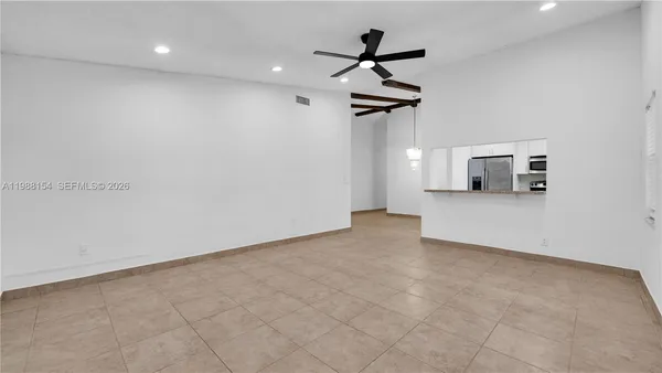 an empty room with ceiling fan and windows
