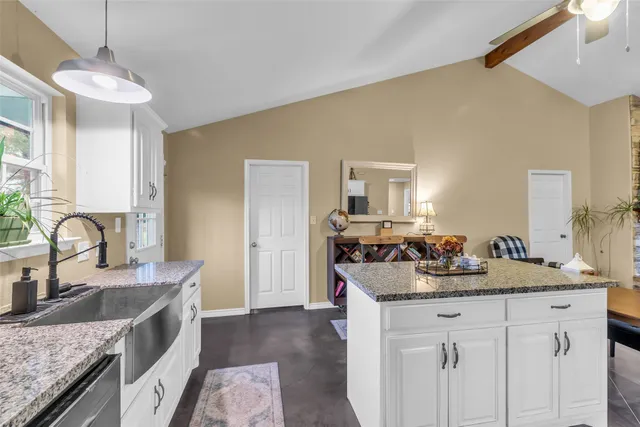a kitchen with a granite countertop sink and white cabinets with wooden floor