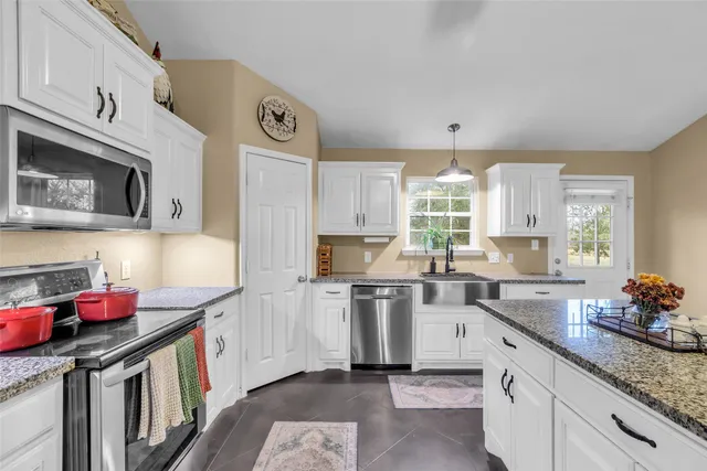 a kitchen with stainless steel appliances granite countertop a sink dishwasher stove and cabinets with wooden floor