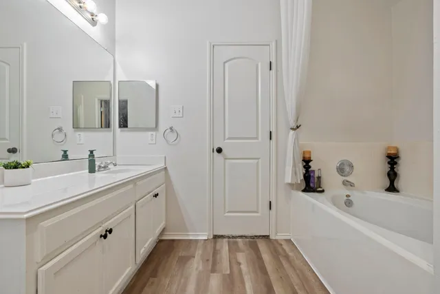 a bathroom with a tub sink and mirror