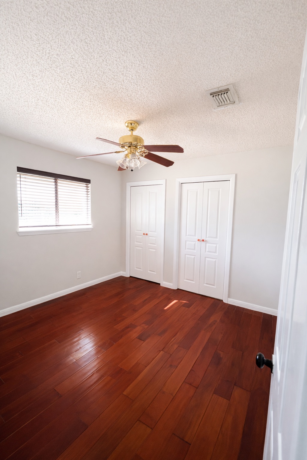 4500 Woodmoor Circle Austin, TX 78721 - Photo 3 of 6 Unfurnished bedroom with multiple closets, dark wood-style flooring, ceiling fan, and a textured ceiling
