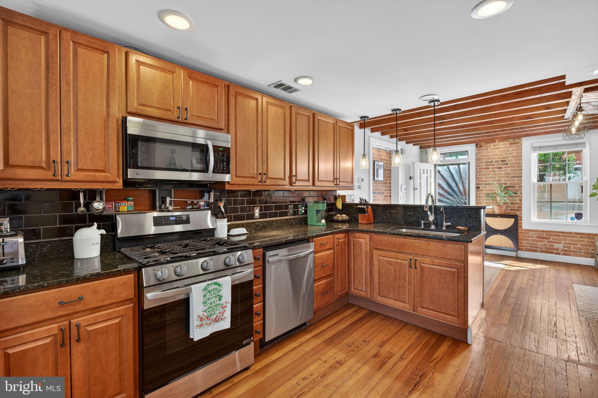 18 South Washington Street Baltimore, MD 21231 - Photo 14 of 57 a kitchen with stainless steel appliances granite countertop wooden cabinets a stove a sink and dishwasher with wooden floor