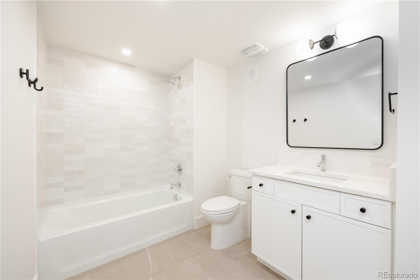 3076 Fenton Street Wheat Ridge, CO 80214 - Photo 30 of 37 a bathroom with a tub sink toilet and mirror