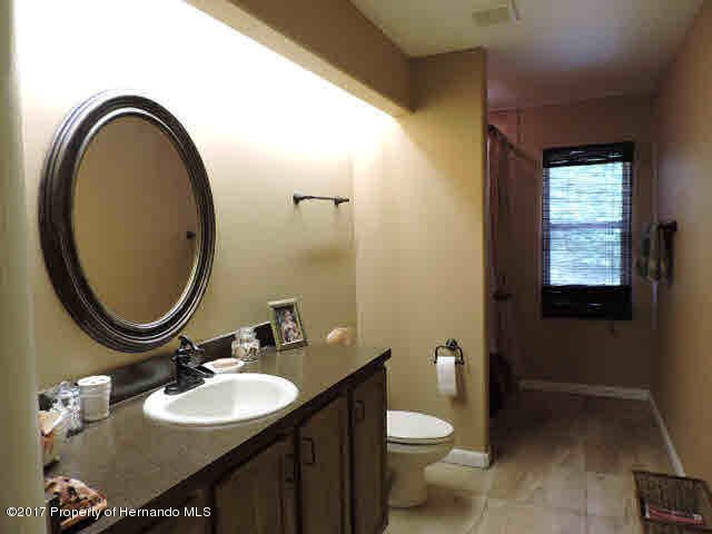 1156 Arlanie Road Brooksville, FL 34604 - Photo 21 of 27 a bathroom with a granite countertop toilet a sink and a mirror