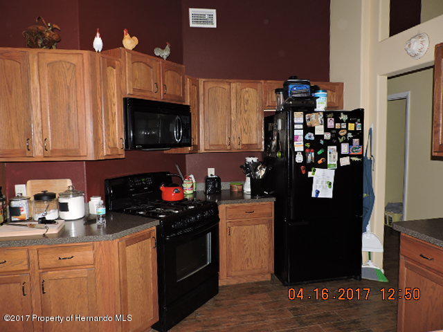 1156 Arlanie Road Brooksville, FL 34604 - Photo 10 of 27 a kitchen with a refrigerator and a stove top oven