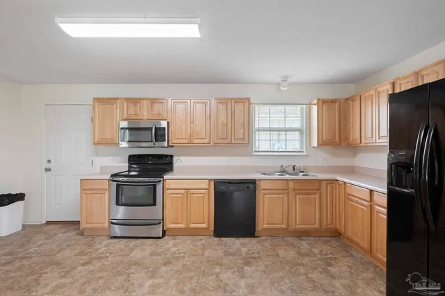 a kitchen with stainless steel appliances granite countertop a sink a stove a refrigerator cabinets and a window