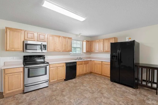 a kitchen with granite countertop a refrigerator stove top oven and sink