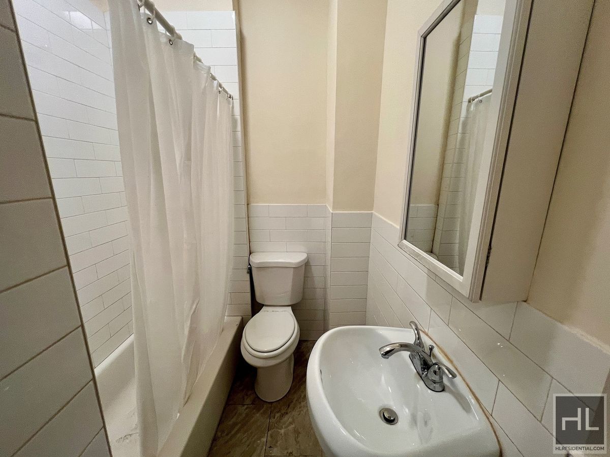 1339 East 91st Street, Unit 1B Brooklyn, NY 11236 - Photo 7 of 12 a bathroom with a sink a toilet and shower curtain