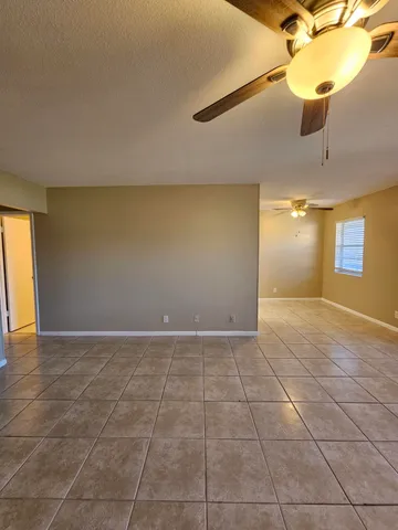 a view of an empty room and window and a chandelier fan