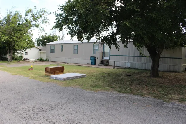 a view of a backyard with large tree and wooden fence