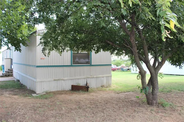 a backyard of a house with plants and large trees
