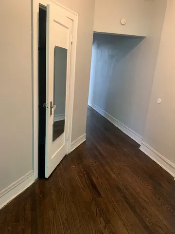 an empty room with wooden floor door and windows