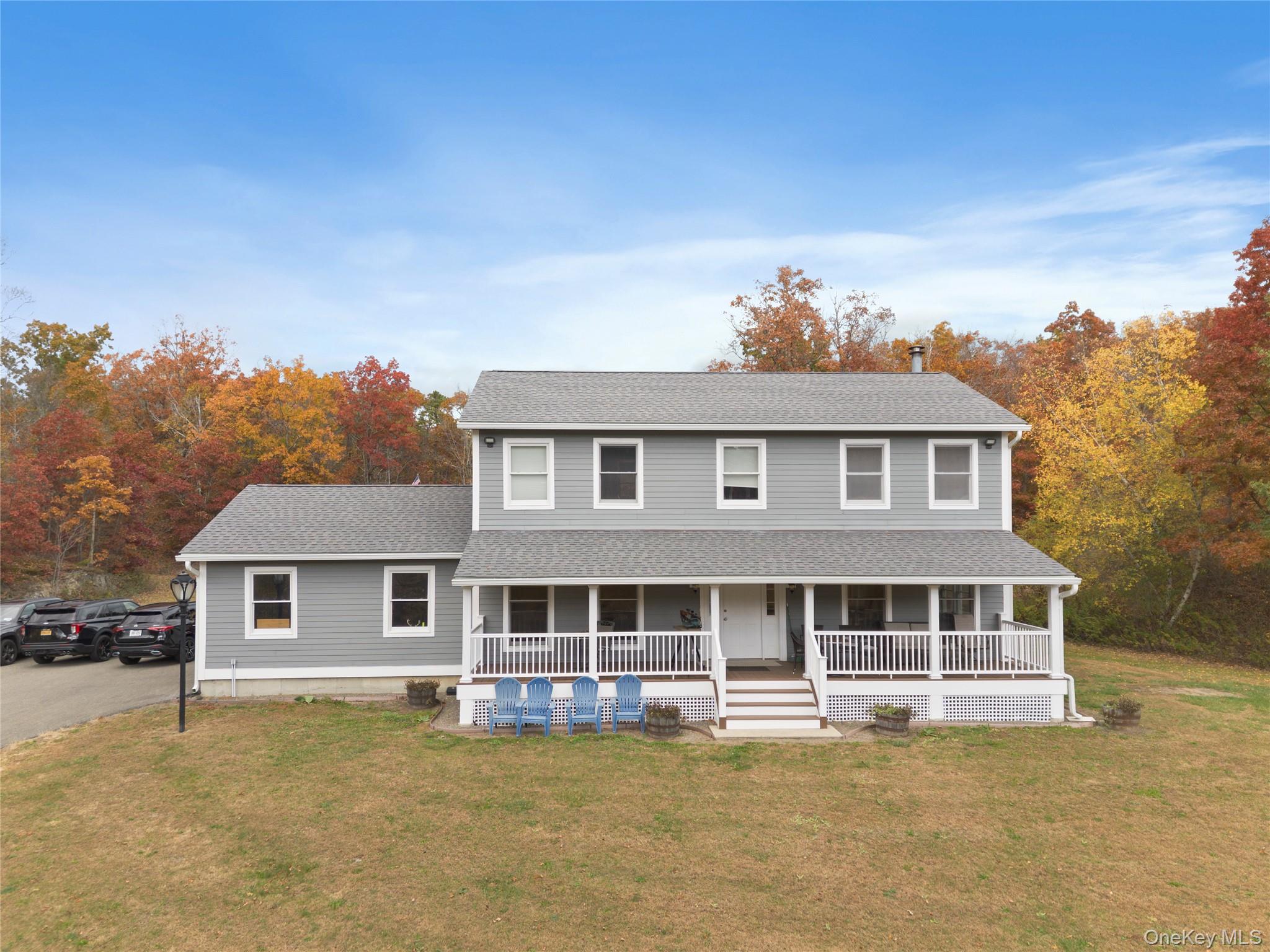 View of front of property featuring a porch, a shingled roof, and a front yard