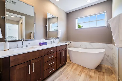 a bathroom with a double vanity sink a mirror and a bathtub