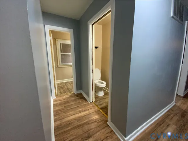 a view of a hallway with wooden floor and a livingroom