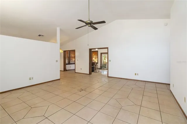 an empty room with ceiling fan and carpet