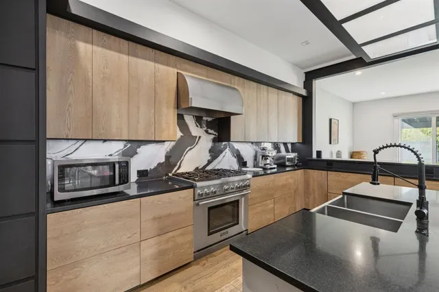 a kitchen with stainless steel appliances granite countertop a stove a sink and a microwave