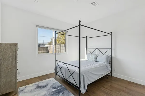 a bedroom with wooden floor and a window