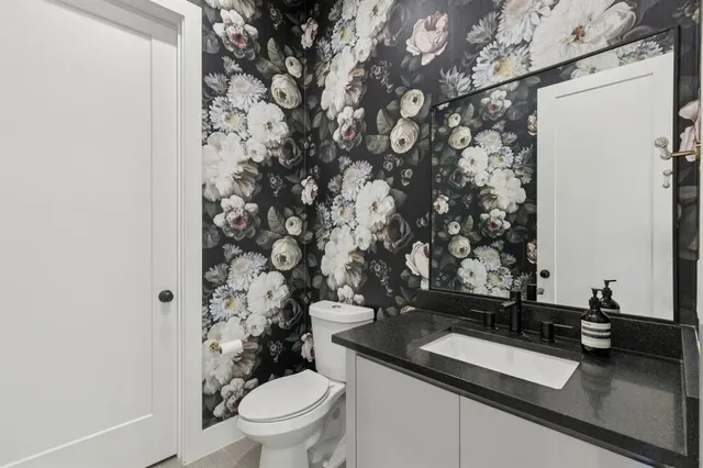 a bathroom with a granite countertop sink and a toilet