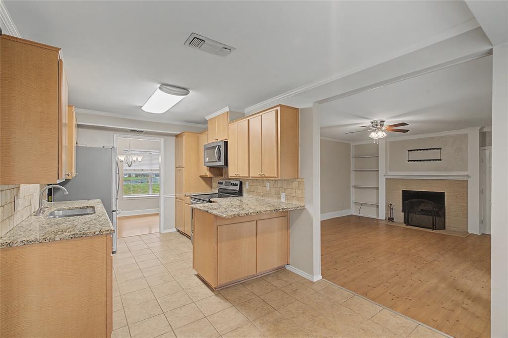 3200 Hickory Court Bedford, TX 76021 - Photo 12 of 30 Kitchen with backsplash, light wood finish cabinetry, light stone counters, light tile patterned flooring, and crown molding