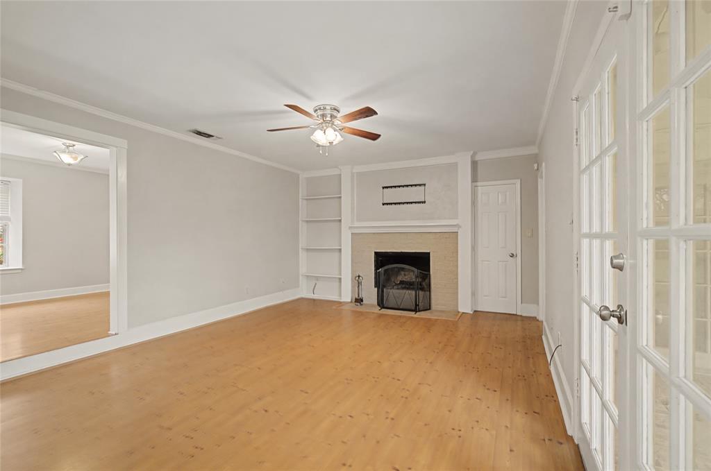 3200 Hickory Court Bedford, TX 76021 - Photo 13 of 30 Unfurnished living room featuring built in shelves, a ceiling fan, light wood-style floors, crown molding, and a fireplace with flush hearth