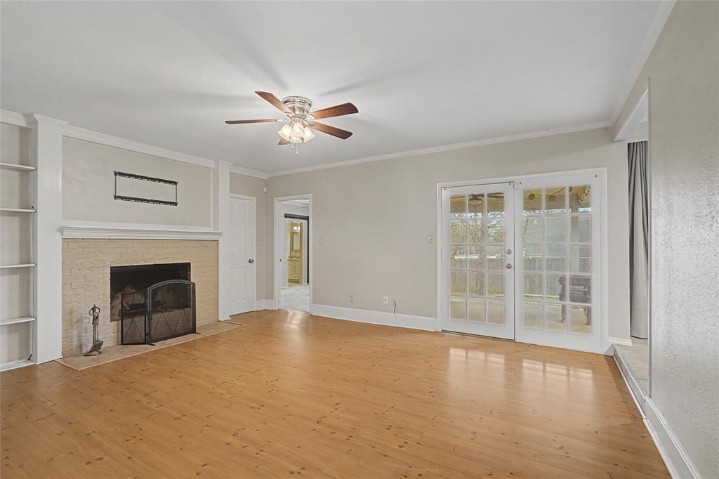 3200 Hickory Court Bedford, TX 76021 - Photo 14 of 30 Unfurnished living room featuring built in features, crown molding, light wood-style flooring, a ceiling fan, and a fireplace